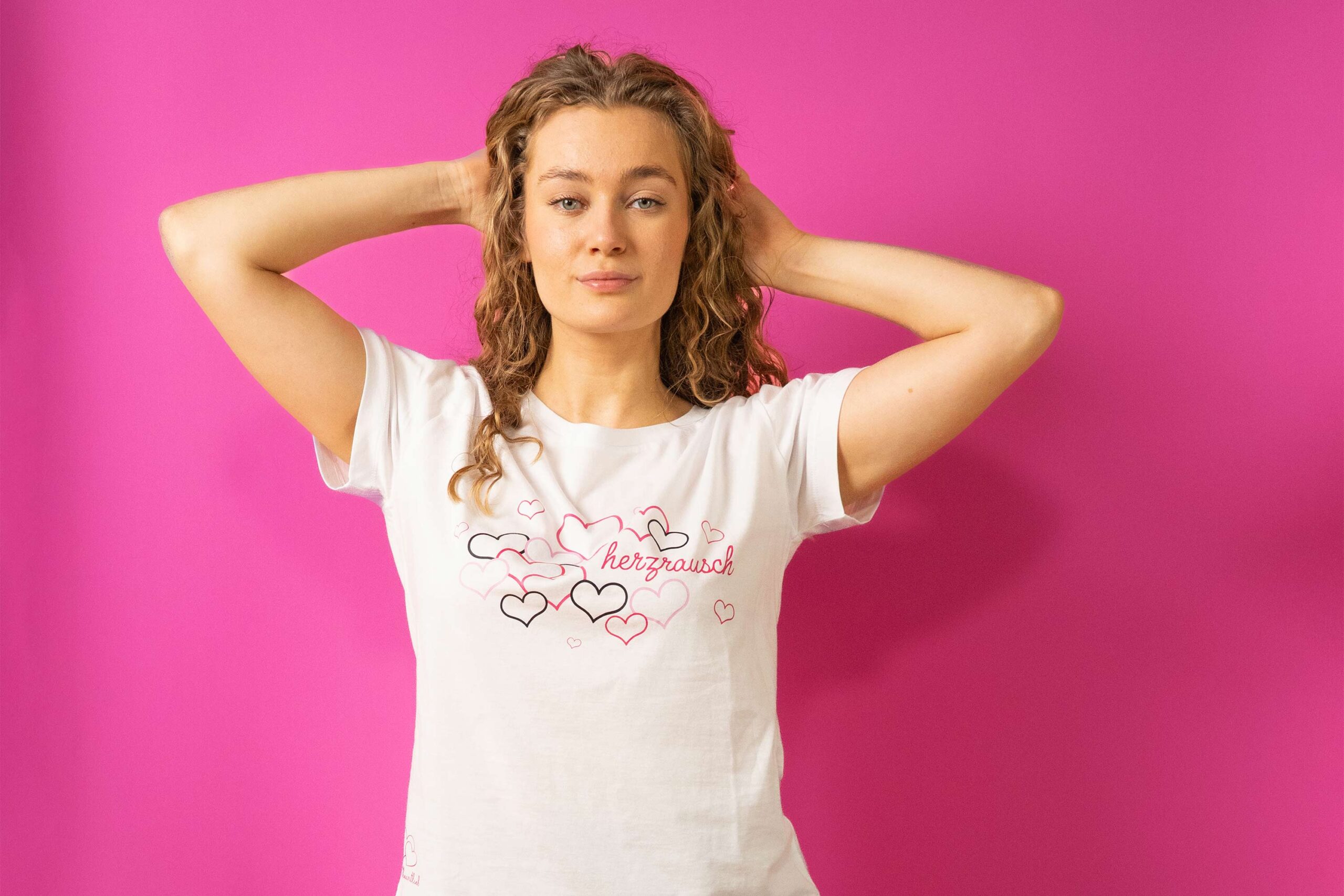 Eine Junge Frau trägt ein Trueheartlieb T-Shirt in Weiß mit "herzrausch" motiv