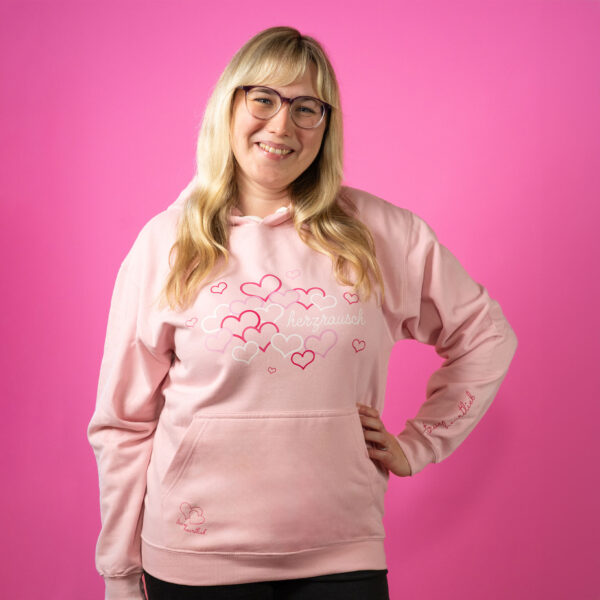 Blonde Frau im rosa Trueheartlieb-Hoodie mit Herzrausch Motiv