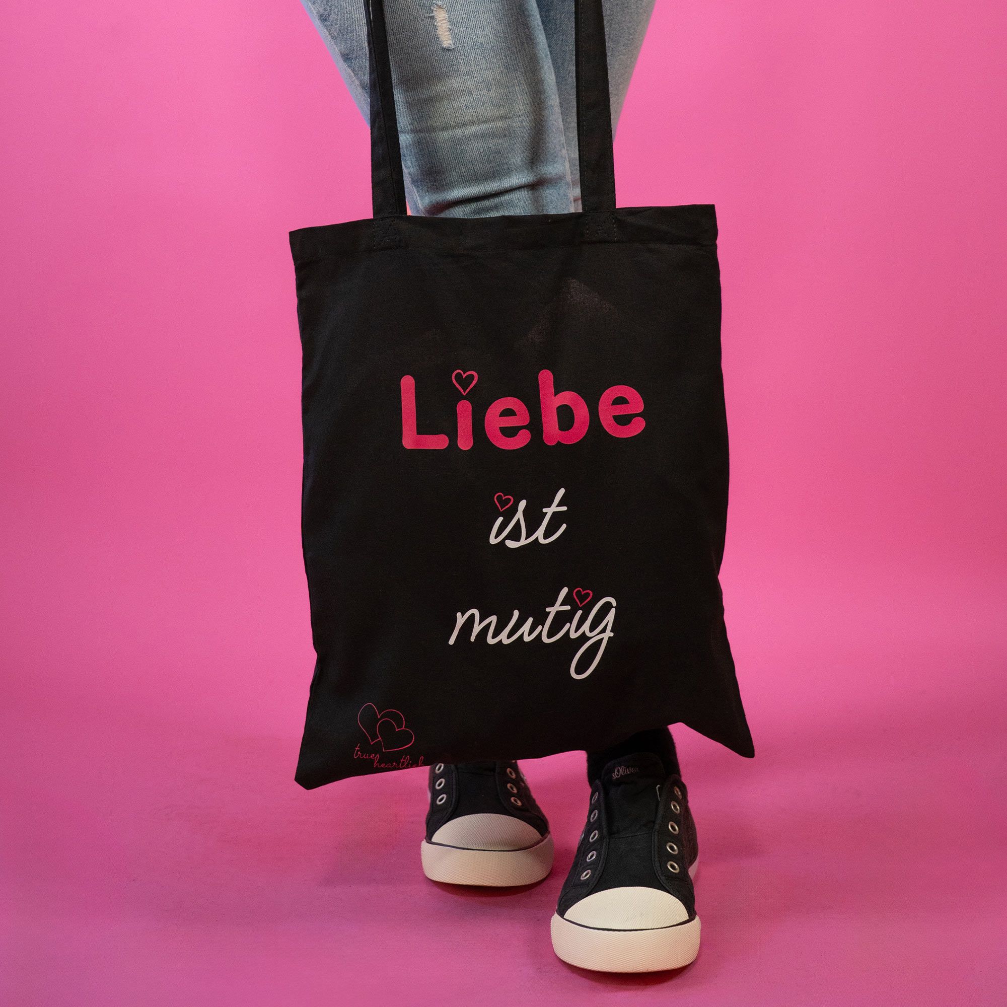Frau trägt Trueheartlieb Tasche in Schwarz mit Liebe ist Mutig Motiv