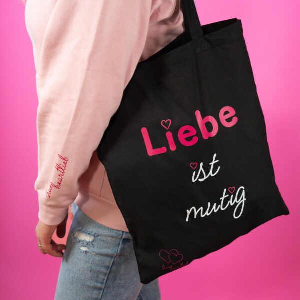 Frau trägt Trueheartlieb Tasche in Schwarz mit Liebe ist Mutig Motiv